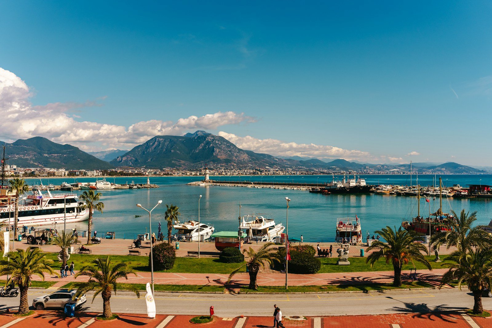 Alanya harbour with boats, palm trees and mountains behind the waterfront
