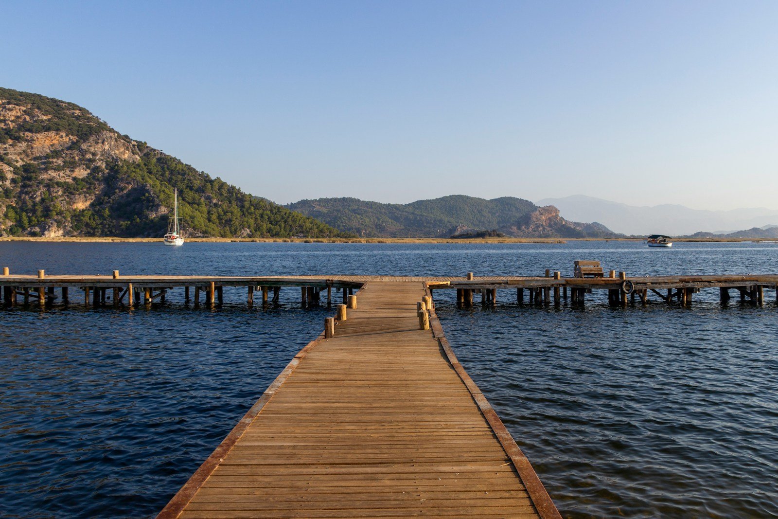 Wooden pier, boats and wooded hills beside the water in Fethiye, Turkey